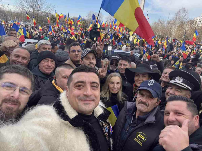 George Simion Antena 3 în mijlocul susținătorilor AUR la un protest, ținând un steag tricolor.